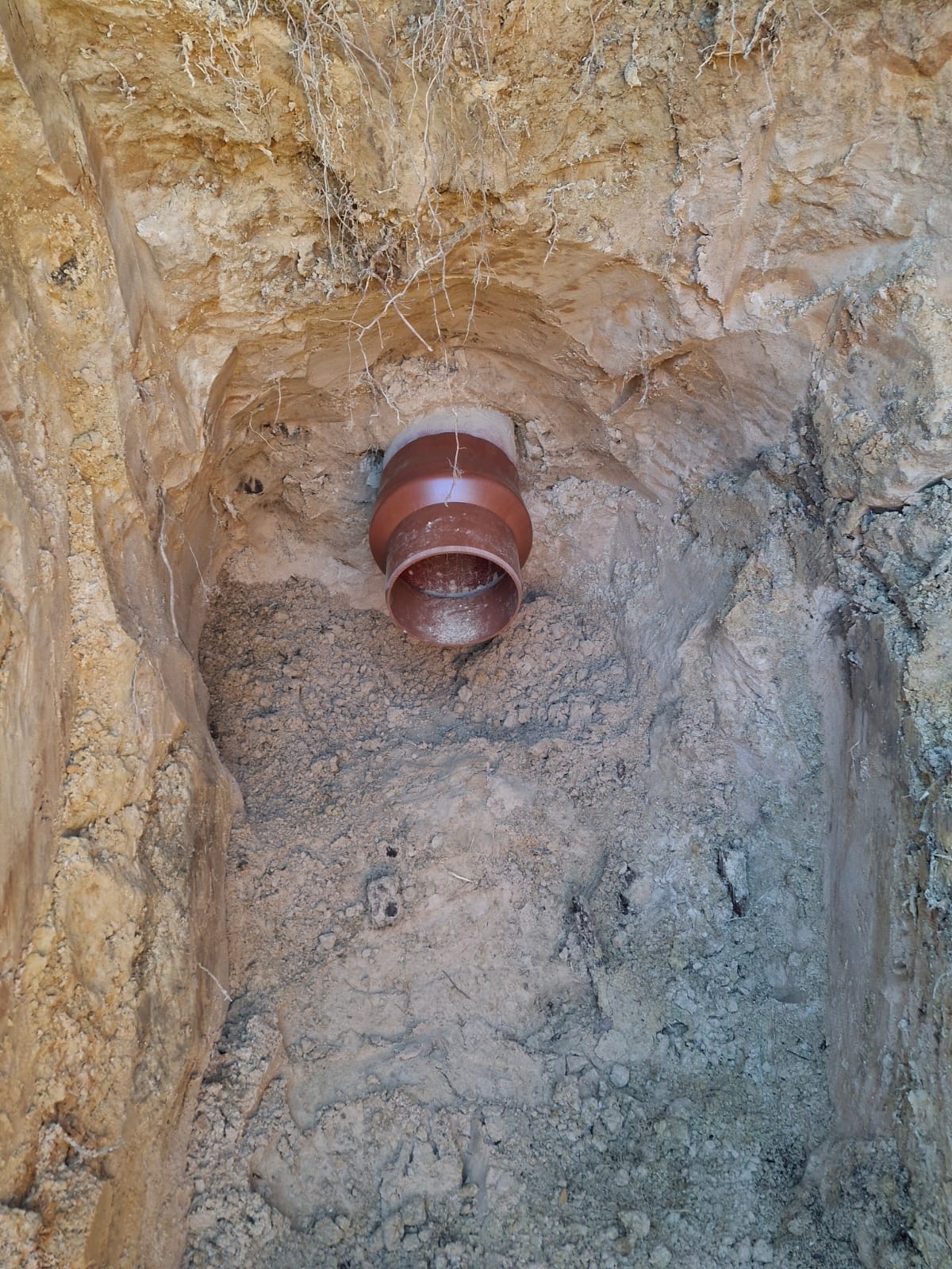 Oranžā kanalizācijas caurule tranšejā